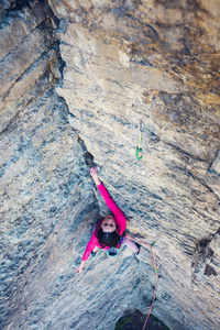 女孩爬上岩石。女人克服了艰难的攀登路线。岩石上的攀岩者。户外运动