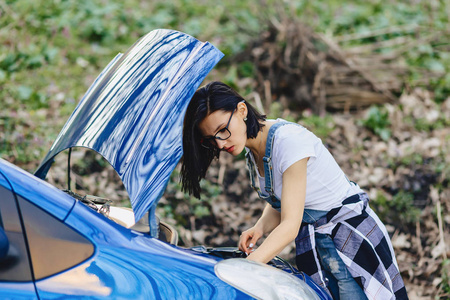 女孩修理汽车与一个开放敞篷在路单独