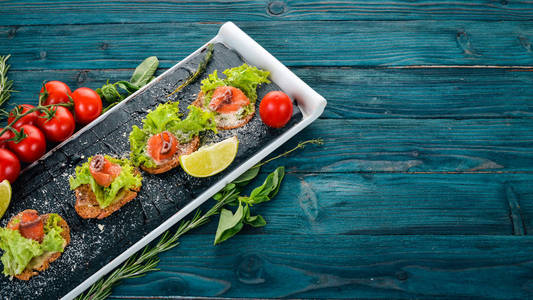 三明治配鲑鱼和沙拉叶。在一个木质的背景。顶部视图。复制空间