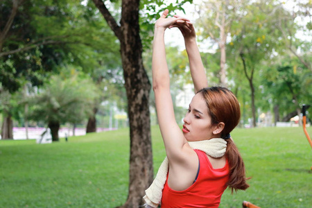 健康的亚洲妇女在公园奔跑前伸展双臂。健身与锻炼理念