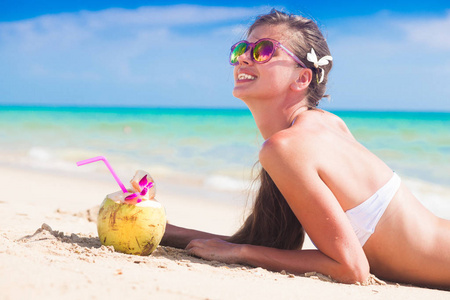 与热带海滩上的新鲜椰子果汁比基尼的女人