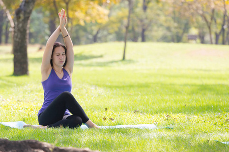 假期年轻女子做瑜伽姿势冥想在公共公园运动健康概念