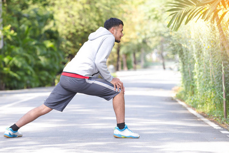 健身运动年轻人赛跑者在公园里做伸展运动。健康理念