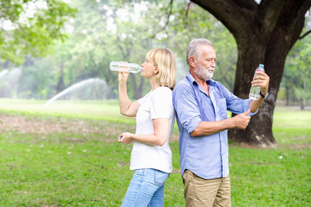 在公园里站着喝水的肖像老人夫妇