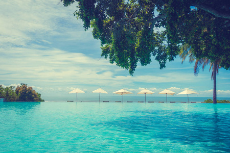 美丽的豪华雨伞和椅子周围的游泳池在酒店和度假村的旅游和度假