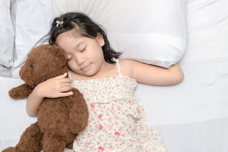 小女孩睡觉与泰迪熊在床上, 健康护理和放松概念