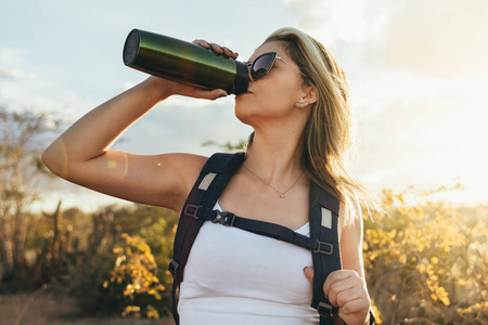在巴西 Caatinga 徒步旅行时, 妇女在喝瓶装水时休息