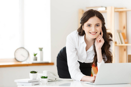 一个漂亮的年轻女子在站在笔记本电脑和笔记本上学习或工作的肖像