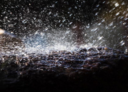 雨中淋湿的石头。雨水落到石头上。水在它们周围流动和飞溅