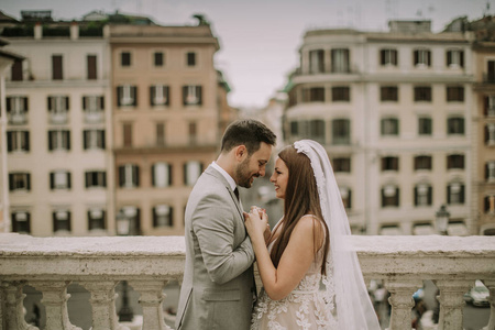 年轻迷人的新婚夫妇摆在罗马与美丽和古老的建筑背景