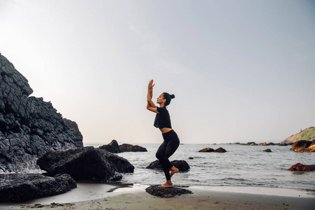 ung frisk kvinna utvar yoga p stranden vid solnedgngen