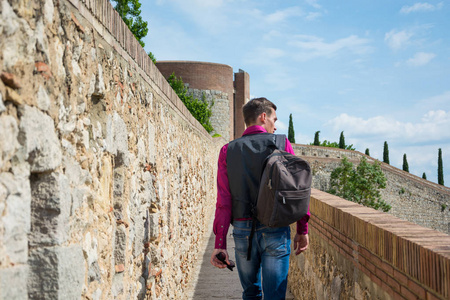 西班牙赫罗纳, 一个带着背包行走在堡垒墙上 Passeig Murala 的年轻游客。看法堡垒墙壁在赫罗纳, 风景