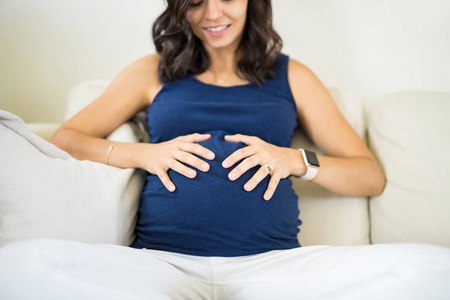 中成年孕妇触摸腹部的感情, 而在沙发上放松在家