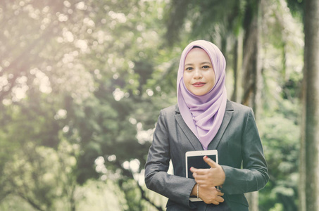 成功的年轻职业 muslimah 女商人的肖像在公园里拿着一块药片