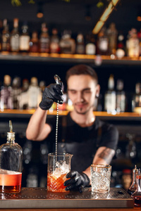 鸡尾酒吧。酒保在酒吧柜台做鸡尾酒。酒保搅拌饮料, 混合烈酒与勺子在玻璃。高分辨率