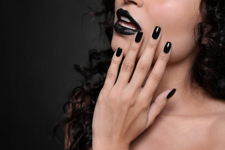 时尚的年轻女子与黑色的指甲黑背景, 特写