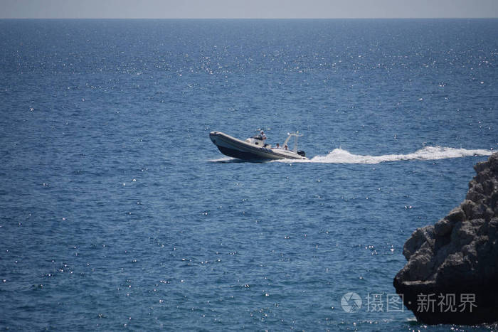 小船是快速漂浮在波浪在阳光下对宽广的蓝色海的背景
