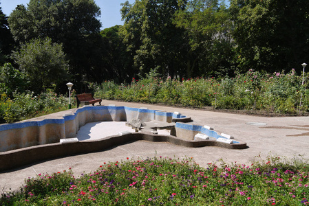 公园中间的一个空水池, 里面有弯曲的长凳和大花坛。