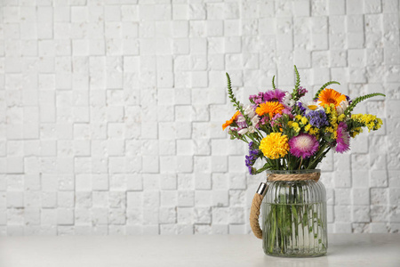 白色砖墙附近桌上有野花的花瓶