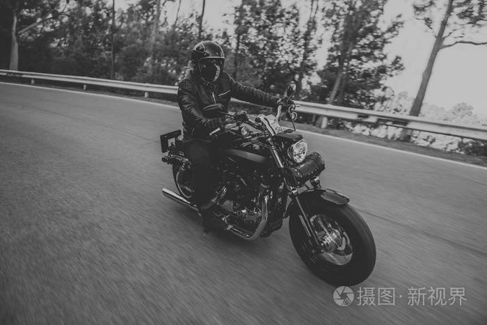 在路上骑着经典摩托车的男人的黑白