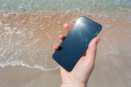 女性手在海滩使用智能手机