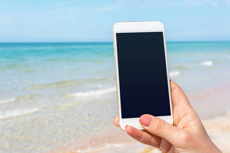 女性手在海滩使用智能手机