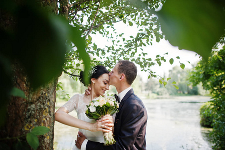 新婚夫妇在他们的婚礼当天在湖边或池塘旁边摆着一棵树。