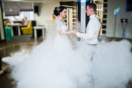 浪漫新婚夫妇表演他们的第一个舞蹈在餐厅与浓烟