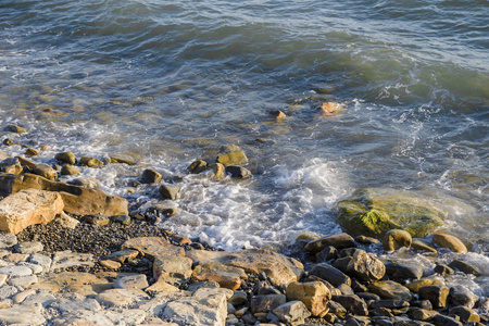 海边鹅卵石上的鹅卵石和阳光照射下的水波