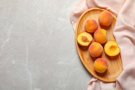 在灰色背景上的美味的成熟桃子板, 顶部视图