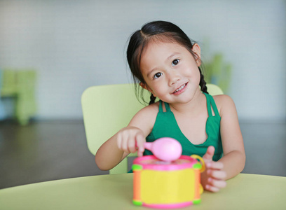 可爱的小亚洲儿童女孩玩打玩具鼓在儿童室