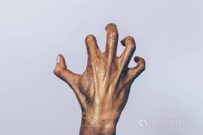毛骨悚然的僵尸手特写.女手掌, 弯曲的手指覆盖着金色的闪光