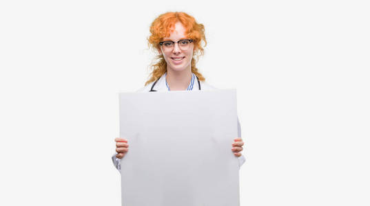 年轻的红头发医生的女人拿着一个快乐的脸站在微笑着一个自信的微笑显示牙齿