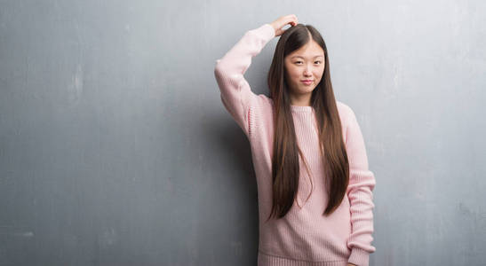 年轻的中国妇女在白色砖墙上伸出舌头, 高兴地用滑稽的表情表达出来。情感概念