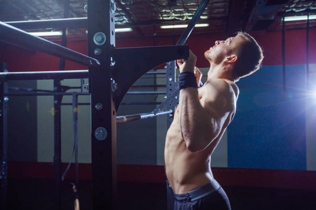 运动员肌肉健身男性模型拉上水平杆在健身房。十字式适合