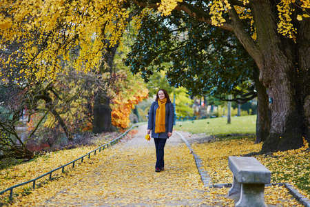 微笑的年轻妇女在公园散步在明亮的秋天天