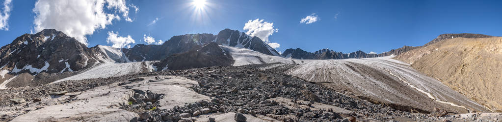 美丽的冰川的壮观的全景与裂缝, 雪, 石头和冰打破高在山对蓝天与云彩
