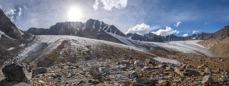 美丽的冰川的壮观的全景与裂缝, 雪, 石头和冰打破高在山对蓝天与云彩