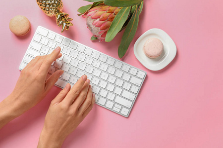 女人用电脑键盘在桌子上装饰着热带花, 上面的景色。创意设计理念