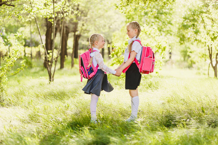 两个小女生在校服牵着手, 看着对方在户外