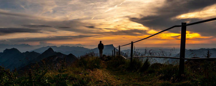 人剪影观看从山顶到湖在日落, brienzer rothorn 瑞士阿尔卑斯全景视图