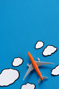 蓝色背景下的玩具平面和纸云的顶部视图, 旅行概念