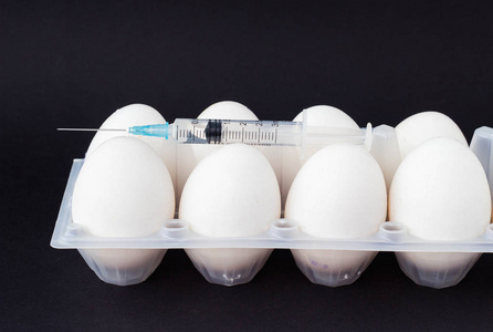 在一个黑色背景的鸡蛋, 注射器注射的激素和补充剂, 特写, 睾丸和抗生素