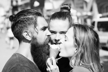 两个漂亮的女孩和残酷的胡子男，舔着冰淇淋