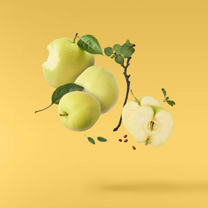 飞在空气绿色新鲜整体和切开苹果并且叶子在黄色背景, 食物悬浮概念, 优质
