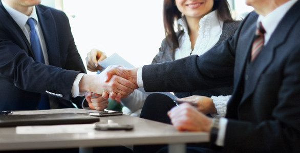 成熟的商人握手达成协议与他的合作伙伴和同事在现代化的办公室