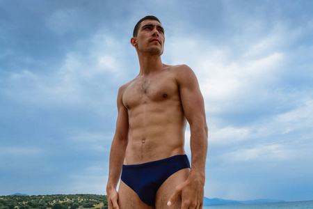 站在 speedo 的海滩上的肌肉男。自由  运动 健康的生活方式的概念