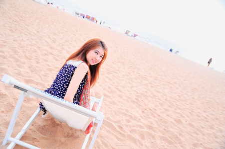亚洲小姐在海滩上的椅子上放松的微笑