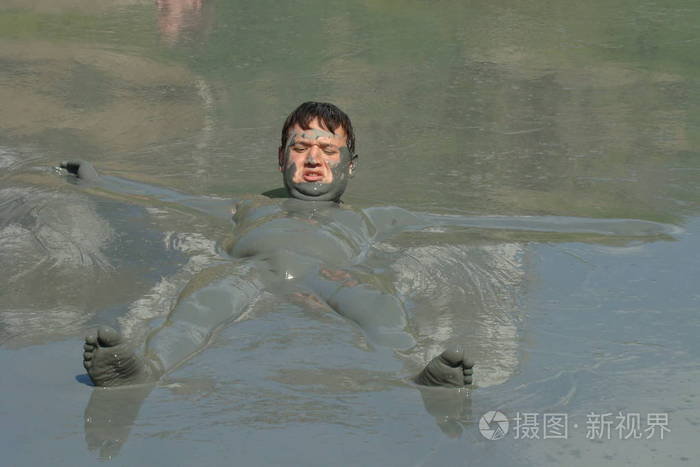 一个男孩在泥地里游泳.洗个泥巴澡