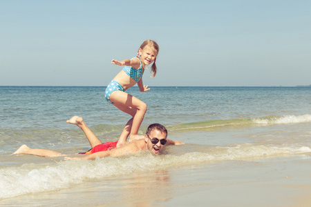 父亲和女儿在一天时间在沙滩上玩